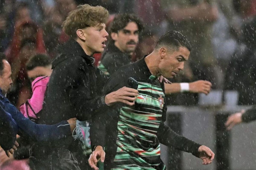 Cristiano Ronaldo bị bất ngờ vì một người hâm mộ xâm nhập vào sân (Ảnh: The Mirror).