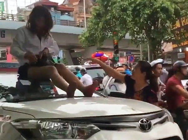 Nữ tài xế taxi mặc váy ngồi nóc ô tô chống đối CSGT